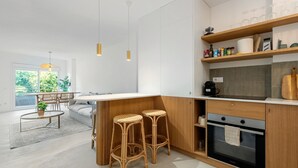 Une cuisine moderne dotée d’un îlot central, de tabourets de bar, d’un four encastré et d’un coin repas avec une table et des chaises.