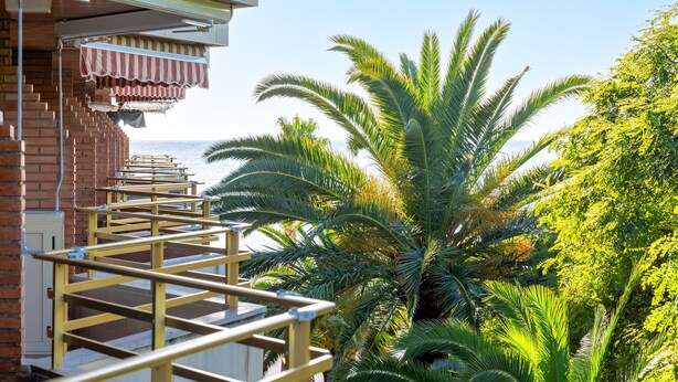 Un bâtiment à la façade en briques, doté d’un espace extérieur abrité avec des sièges et offrant une vue sur la mer.
