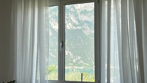 A room with a window overlooking a mountainous landscape. - Villa 'The Queen Of Garda' with Lake View, Private Garden and Balcony (Riva del Garda)