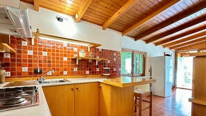 A kitchen with wooden cabinets, a tiled backsplash, a built-in stove, and a window with a view. - Villa 'The Queen Of Garda' with Lake View, Private Garden and Balcony (Riva del Garda)