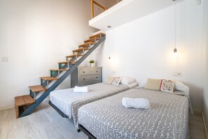 A bedroom with a staircase, two beds, a dresser, and a potted plant.