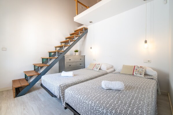 A bedroom with a staircase, two beds, a dresser, and a potted plant. - Holiday Home 'Casa Blanca Porto Cristo' with Wi-Fi and Air Conditioning (Manacor)