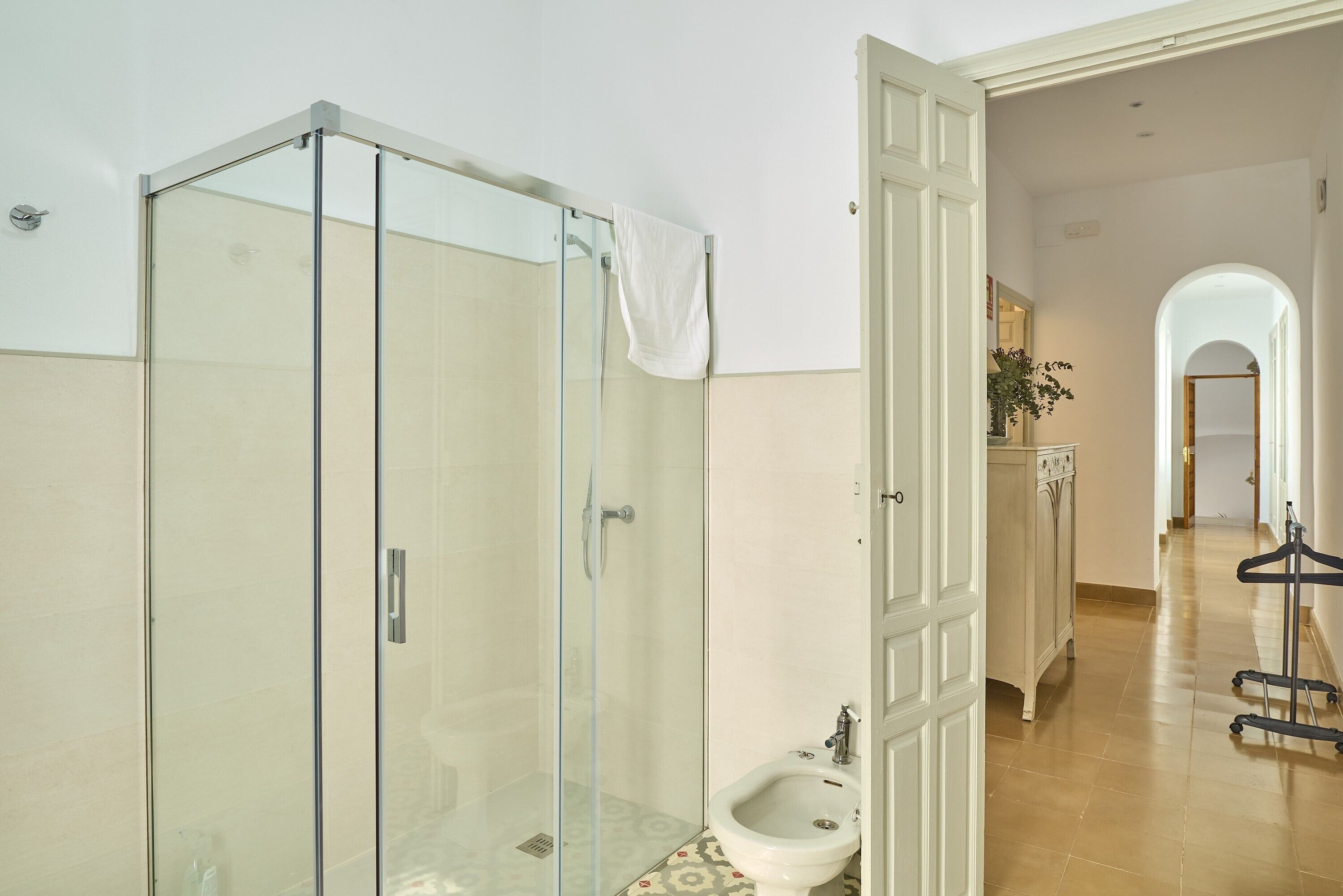 Un baño con cabina de ducha de vidrio, un bidé y un lavamanos blanco.