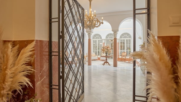 An open doorway leading to a spacious lobby with a chandelier, columns, and a view of the interior. - 2 bedrooms and private bathroom, shared pool, Wi-Fi & air conditioning (Espejo)