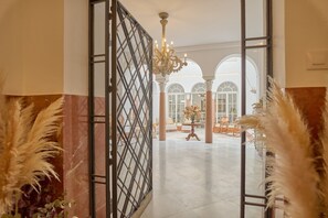 An open doorway leading to a spacious lobby with a chandelier, columns, and a view of the interior. - 2 bedrooms and private bathroom, shared pool, Wi-Fi & air conditioning (Espejo)