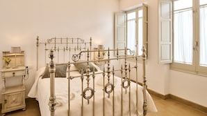 A bedroom with a four-poster bed, a bedside table with a lamp, and a window with curtains. - 2 bedrooms and private bathroom, shared pool, Wi-Fi & air conditioning (Espejo)