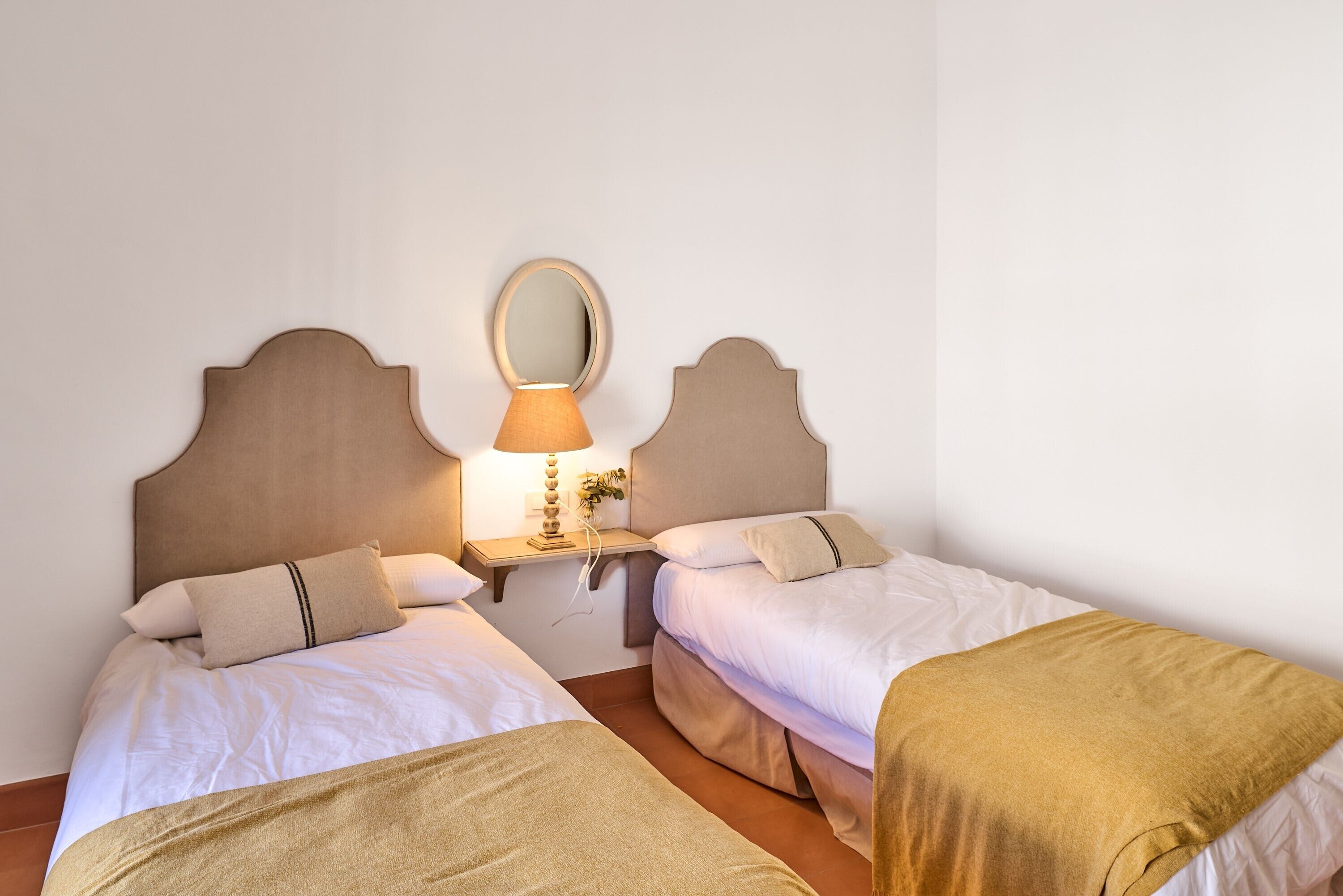 Un lit double avec une tête de lit, une table de chevet avec une lampe et un miroir.
