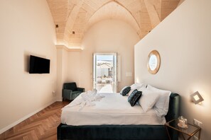 Une chambre avec un lit, une télévision, une chaise et une vue sur l’espace repas.