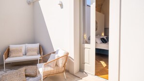A balcony with a sofa, wicker chair, and patterned cushions. - Room 'Relais Luxury Xenia - Ulivo' with Shared Pool, Wi-Fi and Air Conditioning (Sternatia)