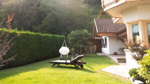 Una casa con balcón, césped y una hamaca colgante.