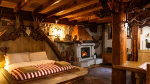 Una habitación rústica con cama, chimenea, vigas de madera y astas.
