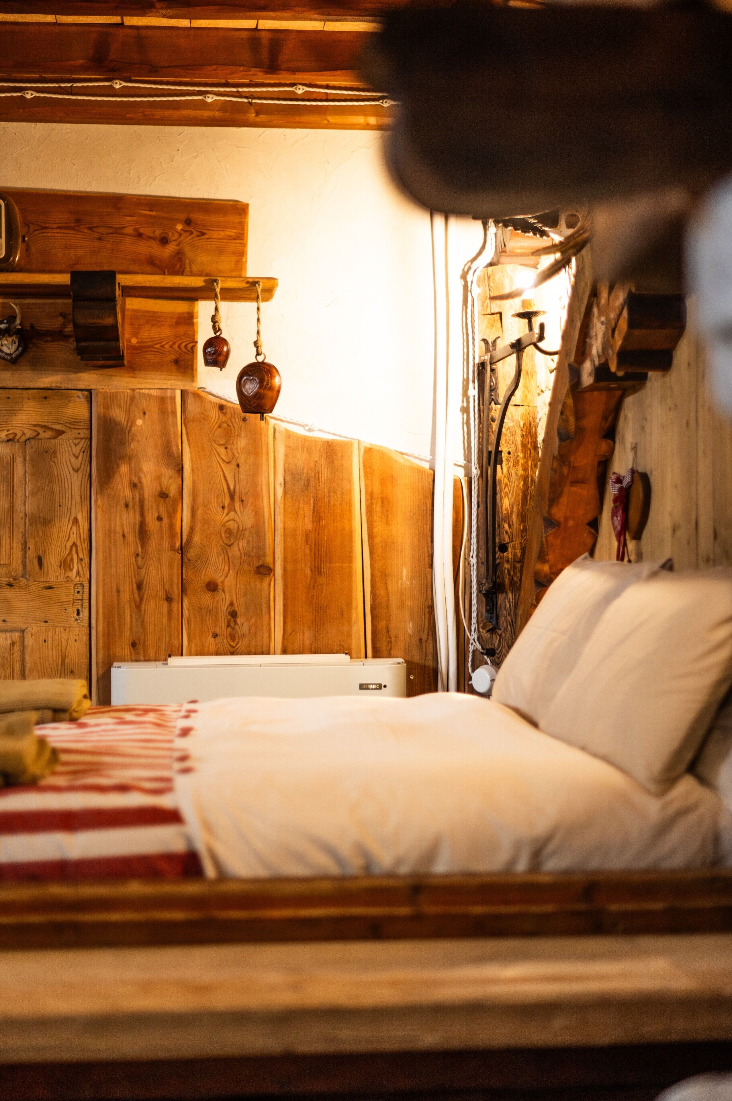 A wooden cabin-style room with a bed, a radiator, and a hanging light fixture.