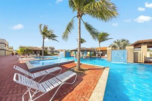 Un espace piscine aménagé avec des chaises longues et des palmiers.