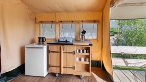 Une cuisine compacte équipée d’un réfrigérateur, d’une machine à café et d’un petit évier.
