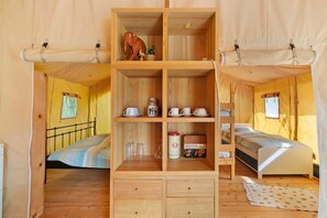 A compact room with two beds, a central wooden cabinet, and a small window.