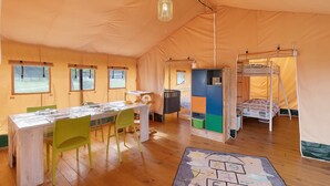 Ein Zeltraum mit Esstisch, Stühlen, Etagenbetten und einem Schrank.