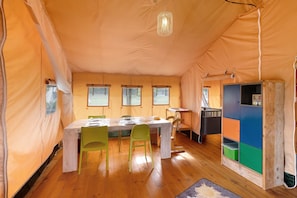 A tent with a dining table, chairs, a bunk bed, and a cabinet.