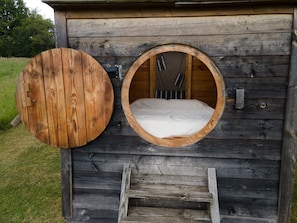 A wooden cabin with a circular window and a ladder leading to a bed. - Null 'Cabane Aux Étoiles' with Shared Terrace and Private Garden (Auriac-du-Périgord)