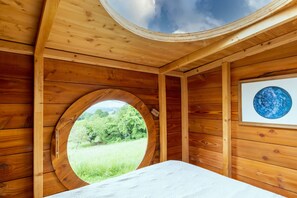 Ein Zimmer aus Holz mit einem Rundfenster, einem Bett und einem gerahmten Globus.