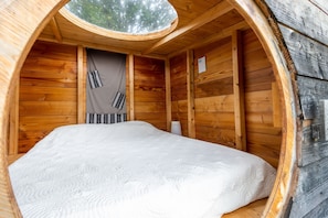 A circular wooden room with a bed, a window, and a small table. - Null 'Cabane Aux Étoiles' with Shared Terrace and Private Garden (Auriac-du-Périgord)