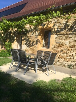 A stone building with a red roof, a window, and a table with chairs outside. - Escape to Domaine de la Salamandre: Nature, Serenity & Sustainable Living (Auriac-du-Périgord)