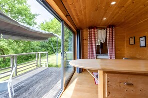 Une cabane en bois dotée d’un balcon, d’une table et offrant une vue sur la verdure.
