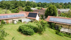Zona residencial con casas equipadas con paneles solares, rodeada de vegetación y un paisaje montañoso.