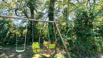 A swing set in a wooded area.