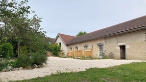 Un bâtiment en pierre avec une allée en gravier et une zone herbeuse.