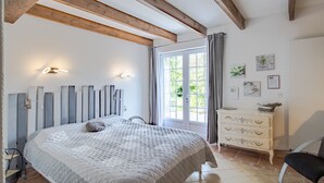 Un dormitorio con cama, cómoda y ventana con cortinas.