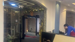 Un espace d’accueil doté d’une porte vitrée, d’un comptoir de réception et d’une statue décorative en or.