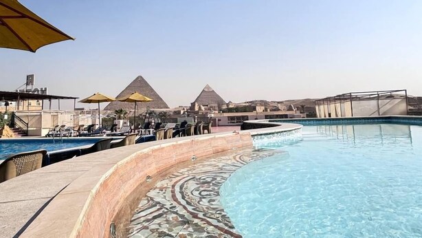 Une piscine offrant une vue dégagée sur les pyramides en arrière-plan.