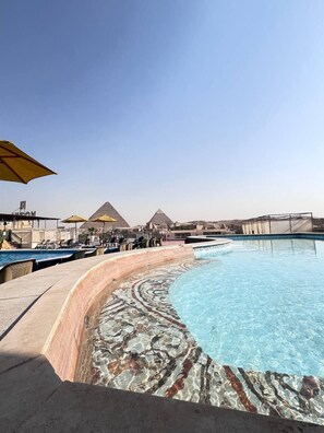 A swimming pool with a clear view of pyramids in the background. -  Elite Pyramids View Inn (Giza)