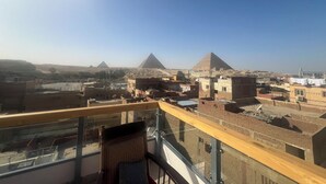Une vue depuis un balcon donnant sur une ville, avec des pyramides visibles au loin.