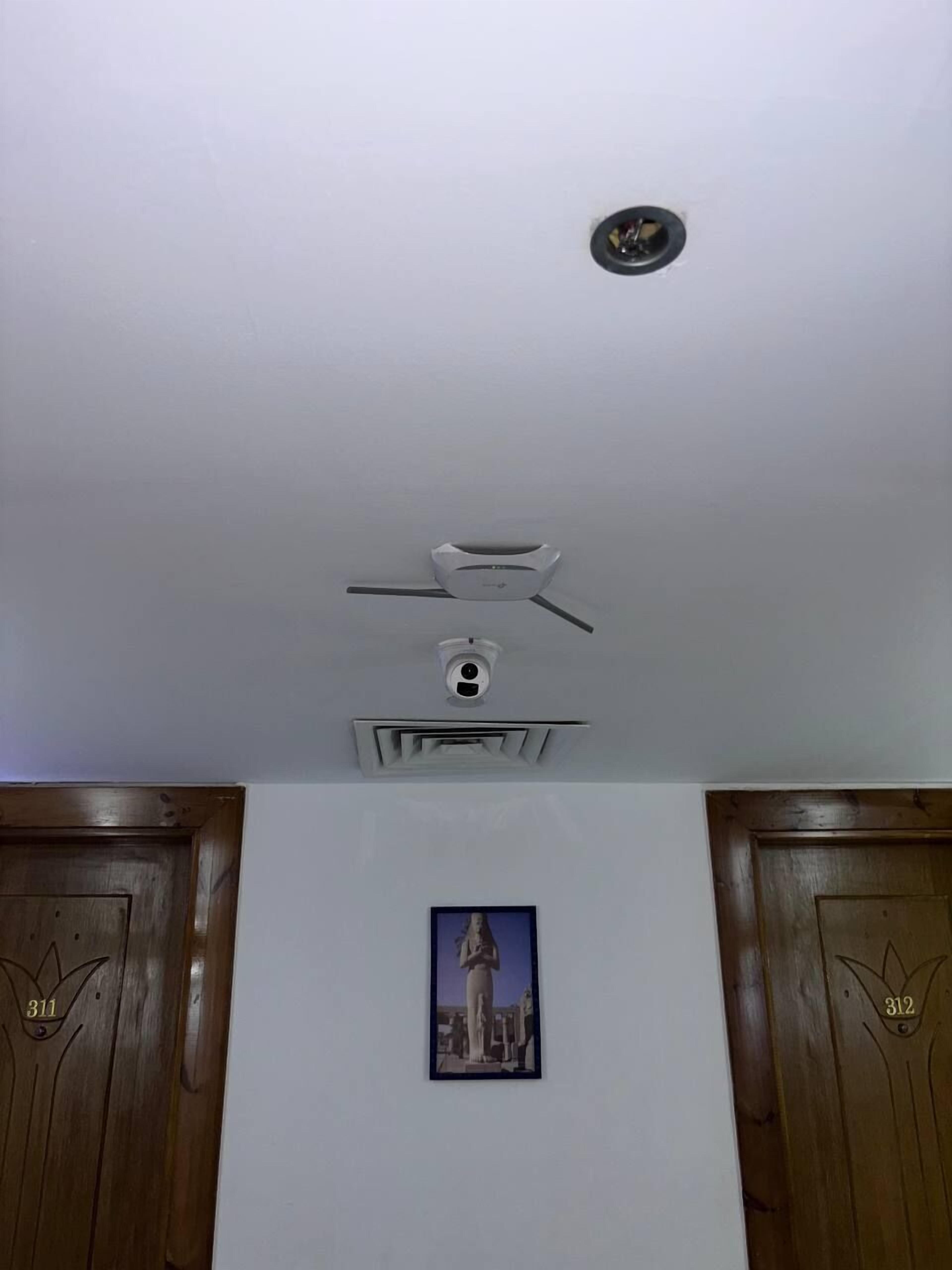 A room with a white ceiling, a recessed light fixture, a smoke detector, and a framed picture on the wall.
