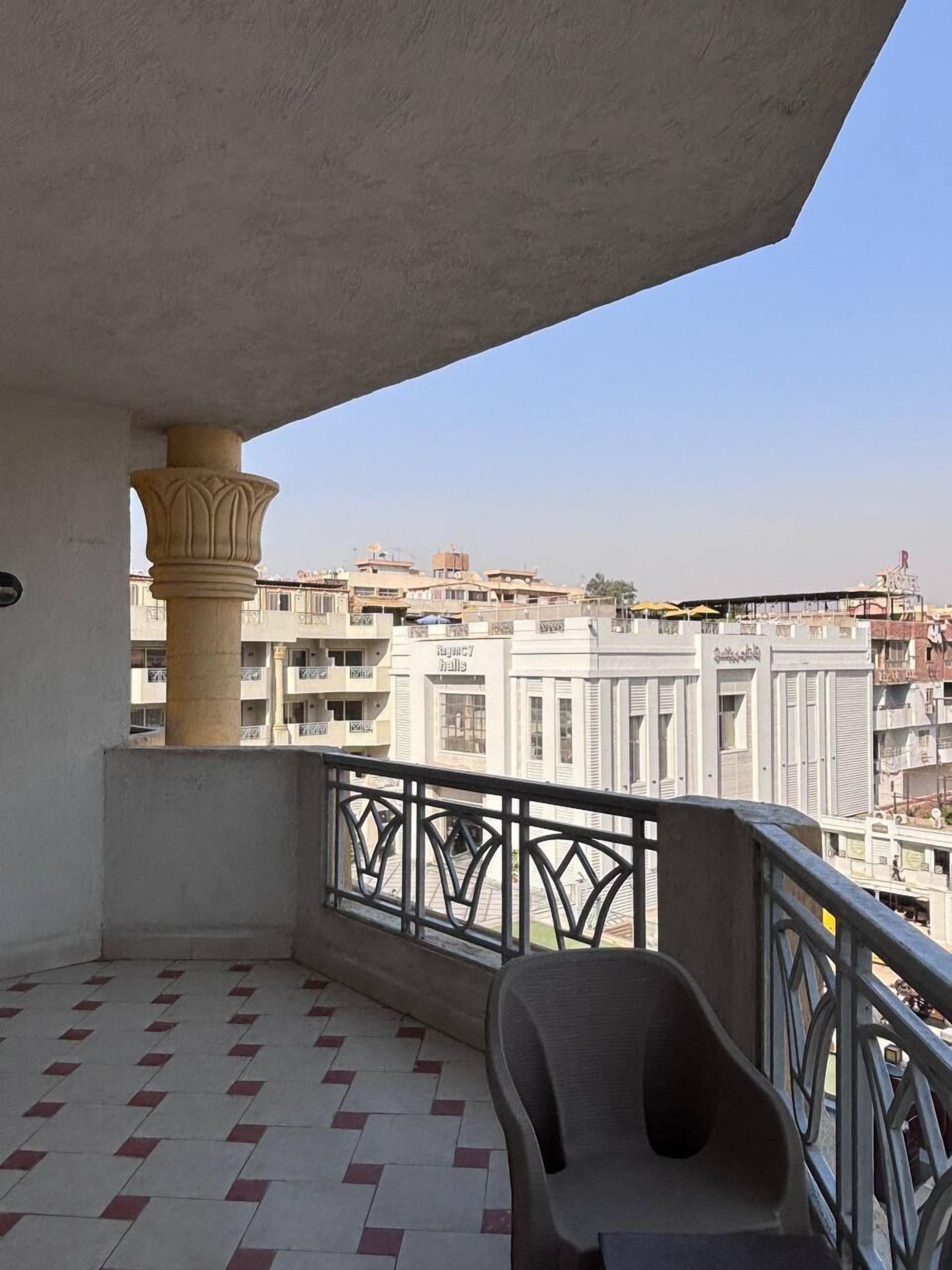 A balcony with a tiled floor, a chair, and a view of surrounding buildings.
