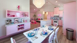A modern kitchen with pink cabinets and a dining area with a white table set for four. - Barbie Themed, Pet Friendly, Parking for 4 Vehicles (Port Aransas)