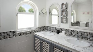 A bathroom with two sinks, a large mirror, and a window.