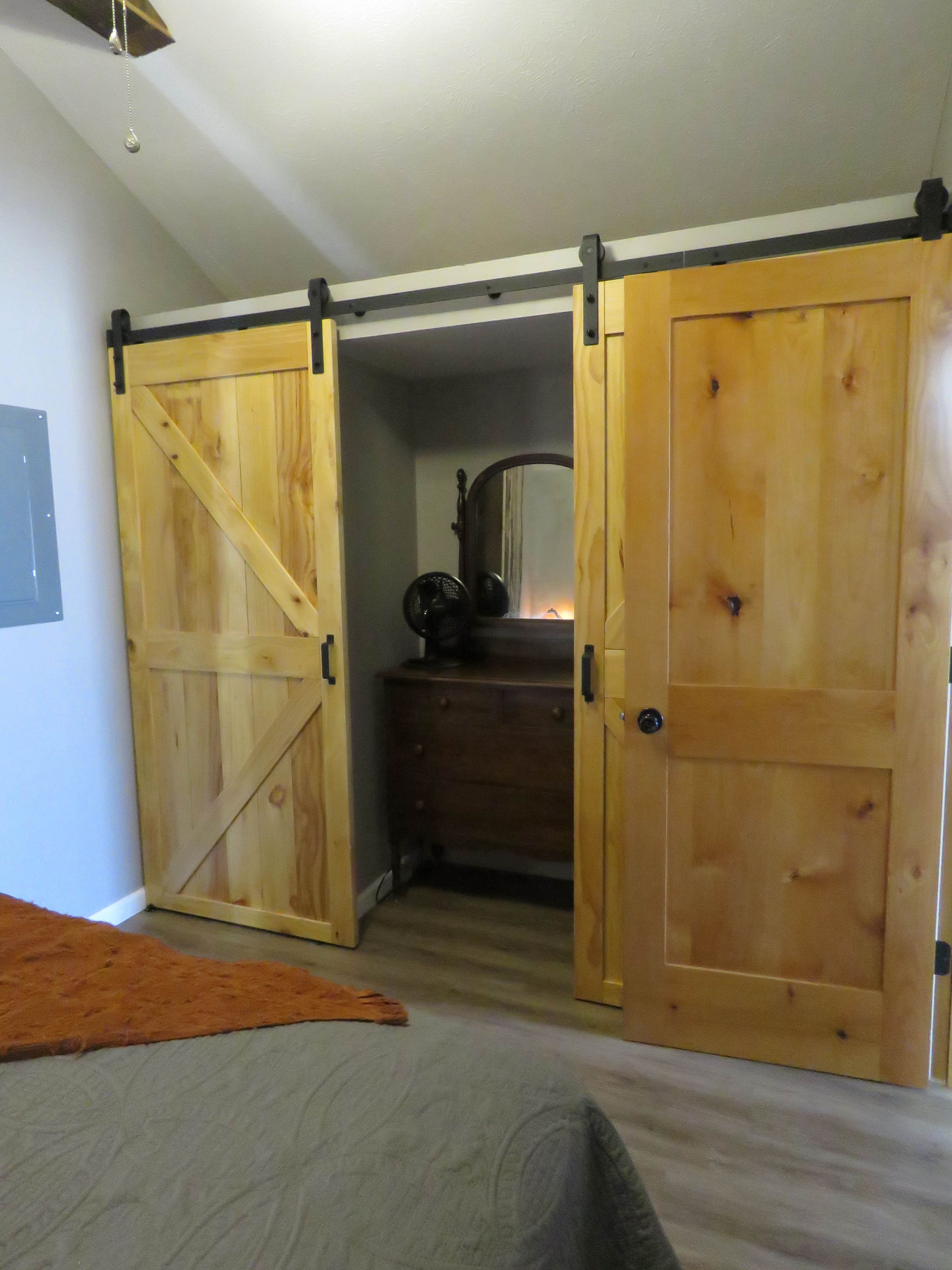 A bedroom with a bed, a dresser, and two sliding doors.