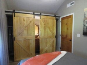 Un dormitorio con una cama, una puerta corredera de madera y una puerta cerrada.