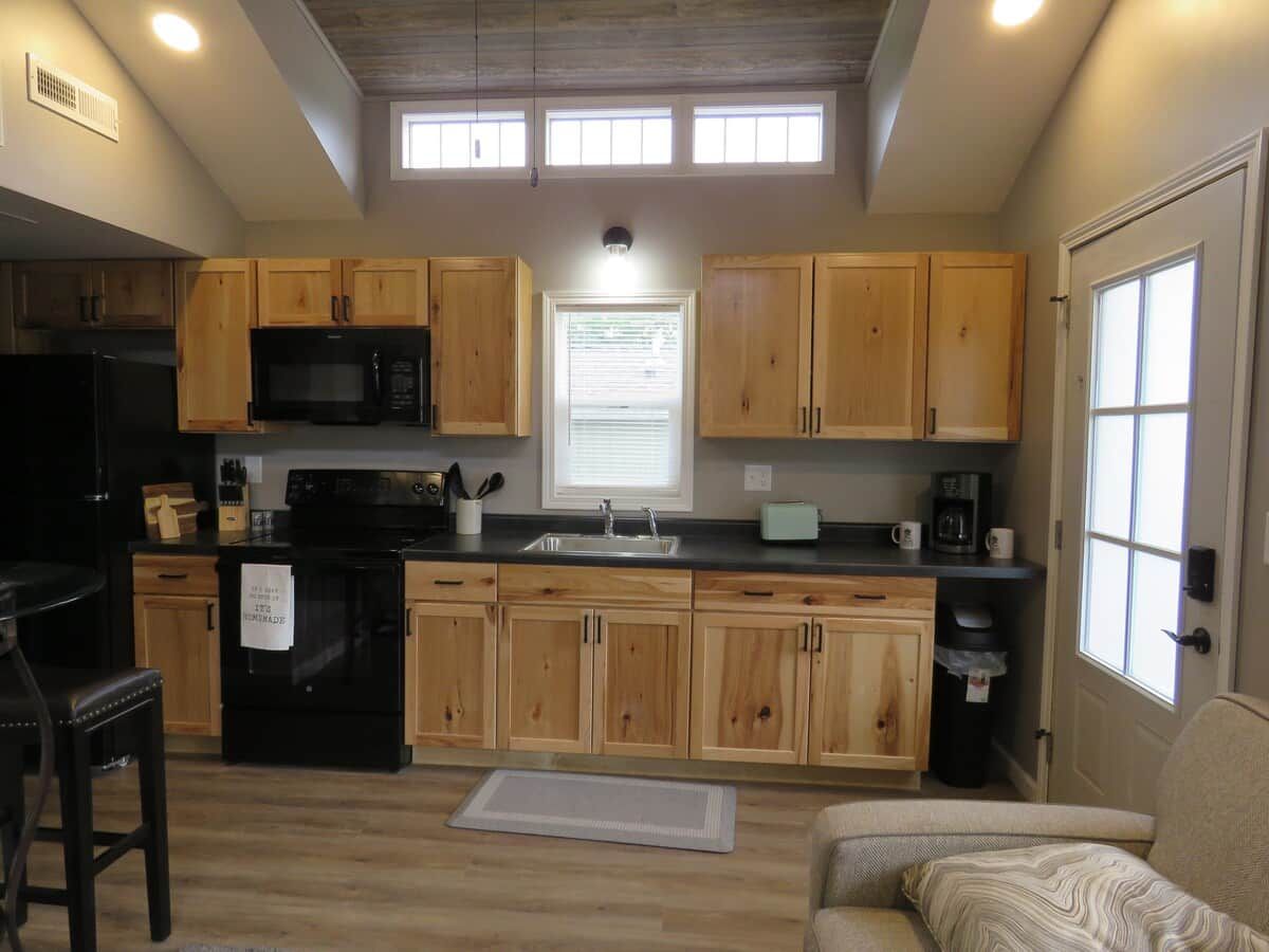 A compact kitchen with wooden cabinets, a black refrigerator, and a microwave.