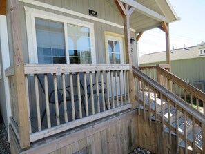 A wooden deck with a railing, a covered porch area, and a sign indicating the property name.
