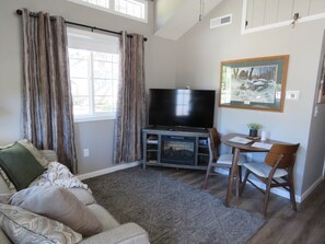 A living room with a sofa, a television, a fireplace, and a dining area with a table and chairs.