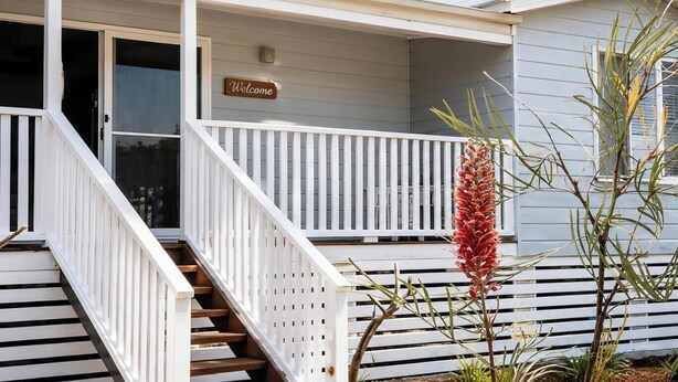 A covered porch with a 'Welcome' sign, a staircase, and a plant. - 2B at Swansea - cosy cottage, outdoor pet friendly (Swansea)