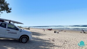 A lifeguard vehicle parked on a sandy beach with waves in the background. - 2B at Swansea - cosy cottage, outdoor pet friendly (Swansea)