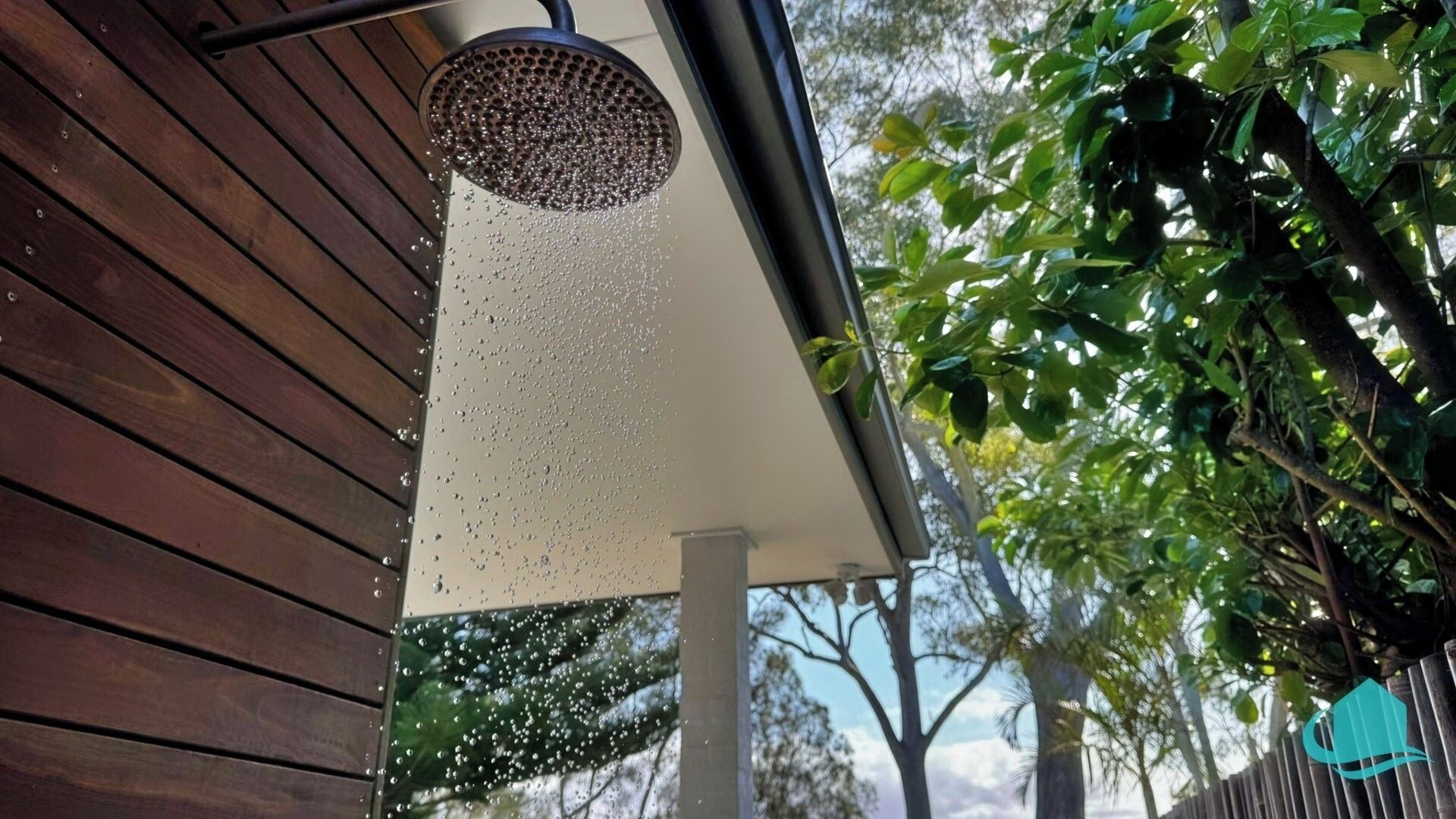 A showerhead with water spraying down, attached to a wooden structure.