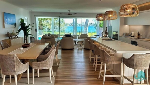 A modern kitchen with a large island, dining area with wicker chairs, and a view of the sea. - Lake Sabai - Waterfront and private pool (Nords Wharf)