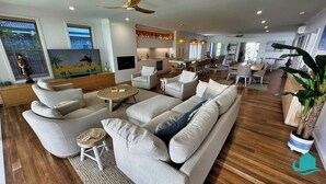 A spacious living area with a sofa set, a coffee table, and a dining area with chairs. - Lake Sabai - Waterfront and private pool (Nords Wharf)
