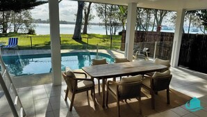 A covered patio with a pool, outdoor seating, and a view of a lake. - Lake Sabai - Waterfront and private pool (Nords Wharf)