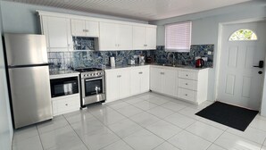 A modern kitchen with white cabinets, a stainless steel refrigerator, a gas stove, and a built-in oven.